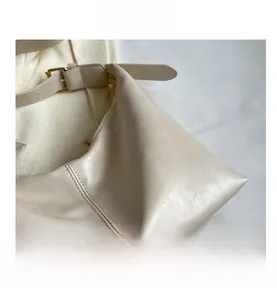 Detailed macro view of the beige textured faux leather fabric and gold metal buckle strap