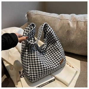 Detailed view of large black and white houndstooth fabric tote bag with brown leather tag