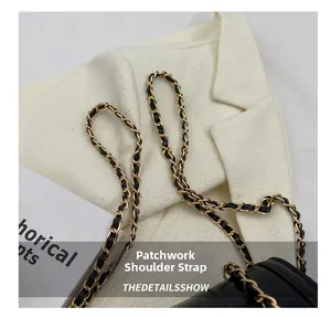 Détail d'un sac en cuir noir avec chaîne en métal doré et bandoulière en cuir