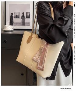 Detail view of off-white leather tote bag with a fashion silk scarf and long shoulder strap