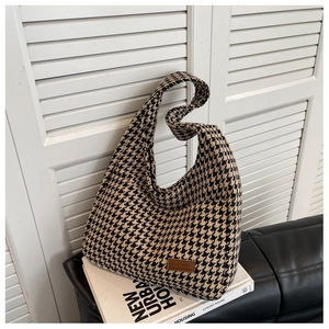 Close-up of black and white houndstooth tote bag with brown leather fashion logo patch