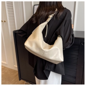 Close-up of beige moon-shaped hobo bag with fringe zipper detail and adjustable strap