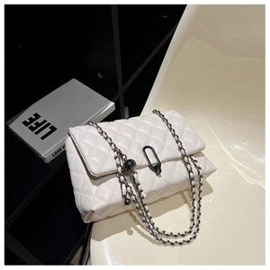 Detail shot of white quilted chain bag with black metallic lock and rhombus pattern