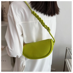Detail of lime green crescent saddle bag with braided strap and lychee grain leather