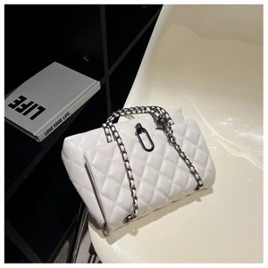 Close-up of white quilted chain bag with black metal buckle on a minimalist chair