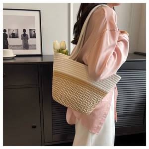 Detail einer großen gewebten Stroh-Tote-Bag in Weiß und Beige von einem Model getragen