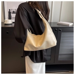 Close-up of a beige leather hobo bag with adjustable strap and soft pleated texture