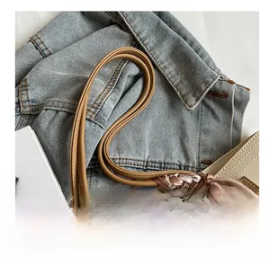 Detail of light beige leather tote with brown handles and decorative striped silk scarf