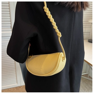 Detail of yellow crescent saddle bag with braided shoulder strap on black blazer