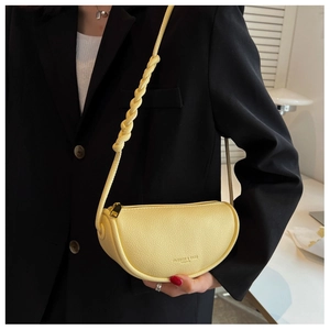 Close-up of light yellow lychee pattern saddle bag with thick woven shoulder strap