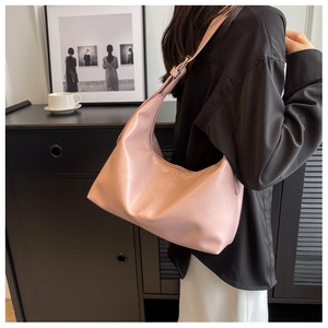 Detail view of pink leather crescent shoulder bag with adjustable strap worn by model