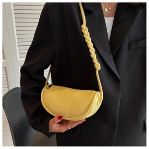 Detail of yellow crescent saddle bag with braided shoulder strap and fashion embossed text