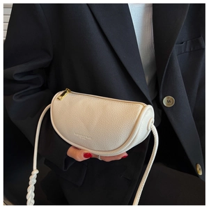Detail of creamy white pebble leather saddle bag with gold zipper on a black blazer