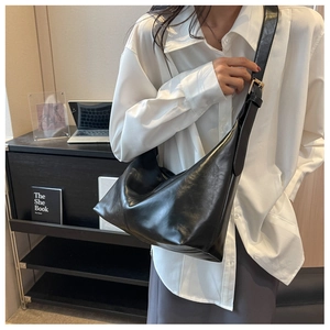 Detail of adjustable wide shoulder strap and gold hardware on black hobo shoulder bag
