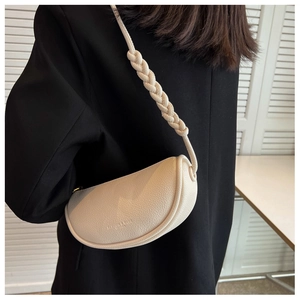 Close-up of off-white leather saddle bag with woven shoulder strap and embossed detail