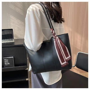 Detail of large black leather tote bag with elegant wine red fashion silk scarf on handle