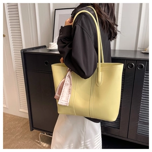 Detail of yellow faux leather tote bag with silk scarf on a model for daily commute
