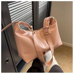 Close-up of pink PU leather dumpling bag with wide shoulder strap and gold metal buckle