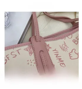 Close-up of pink leather stitching and cartoon graffiti on a cream tote bag