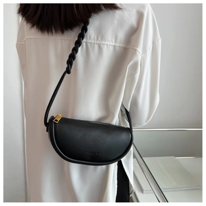 Detail of black pebbled leather saddle bag with woven strap and gold zipper hardware