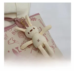 Close-up of a cute knitted bunny charm with gold clasp on a pink tote bag handle