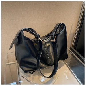 Detail of black hobo bag showing zipper closure and adjustable strap with gold buckle