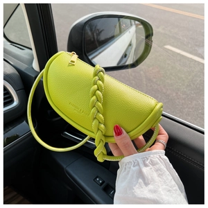 Detail of a bright green half-moon saddle bag with woven handle inside a car interior
