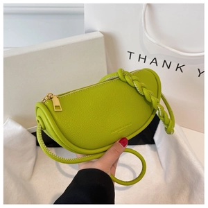 Detail of green pebble leather saddle bag with woven strap and gold zipper closure