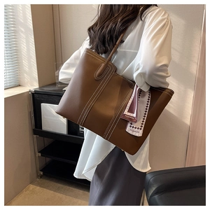 Detail of dark brown tote bag with contrast white stitching and decorative silk scarf