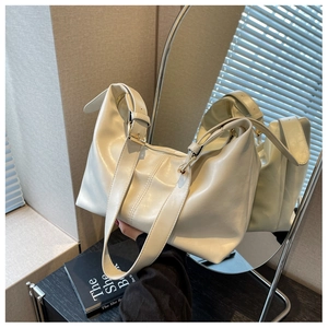 Detail of soft beige leather dumpling bag with wide shoulder strap and gold hardware