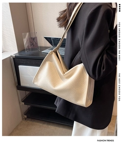 Vista laterale di una borsa tote in pelle martellata color crema indossata da una modella
