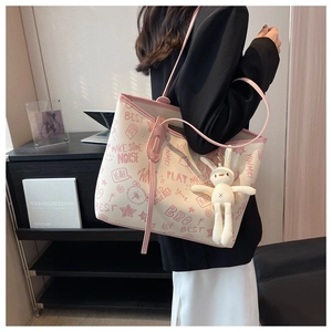 Detail view of cream tote bag with pink graffiti print and cute rabbit plush charm