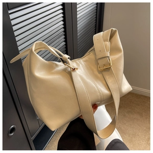 Detail of off-white leather dumpling bag featuring wide shoulder strap and gold metal buckles