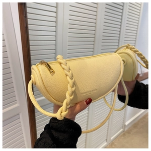 Detail of light yellow crescent saddle bag with pebbled leather and braided handle