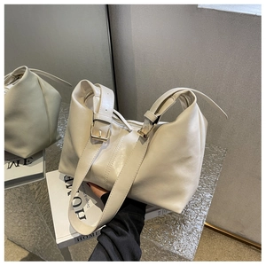 Detail of soft cream faux leather texture and golden buckle on wide strap handbag