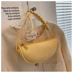 Detail of light yellow saddle bag with lychee grain leather and woven shoulder strap