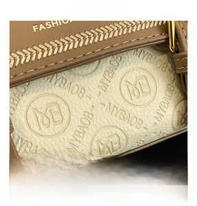 Dettaglio macro della pelle beige martellata con logo in rilievo e cuciture di precisione