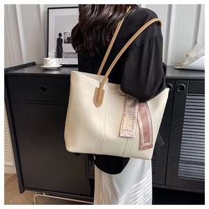 Close-up of cream leather tote bag featuring brown straps and decorative fashion scarf