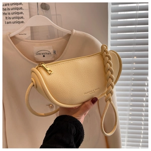 Detail of cream crescent bag with lychee texture leather and woven shoulder strap
