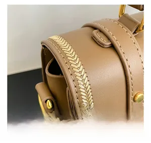 Dettaglio borsa in pelle marrone con cuciture intrecciate e fibbia metallica dorata