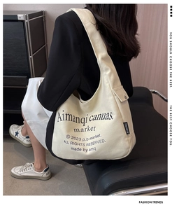 Lifestyle shot of large cream canvas tote bag with black typography and shoulder strap