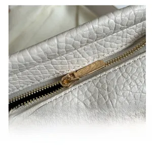 Dettaglio macro di una borsa tote in pelle martellata bianca con cerniera in metallo dorato