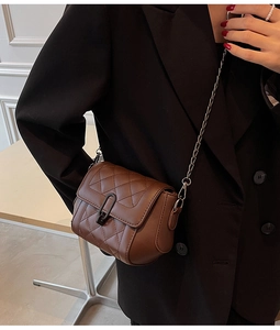 Détail du sac bandoulière matelassé marron avec boucle ovale et chaîne élégante