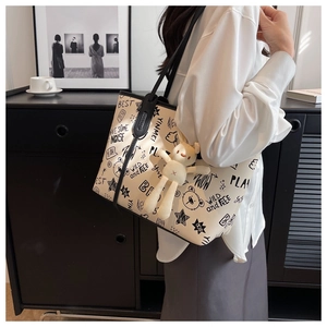 Detail of off-white graffiti tote bag with black letter print and rabbit doll pendant