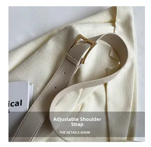 Dettaglio della tracolla regolabile in pelle beige con fibbia dorata lucida e fori