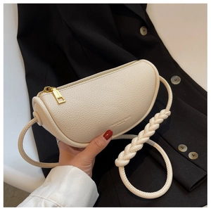 Detail of cream saddle bag with lychee texture and thick woven rope strap on black suit
