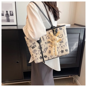 Detail of white graffiti tote bag featuring black sketches and a plush bunny charm
