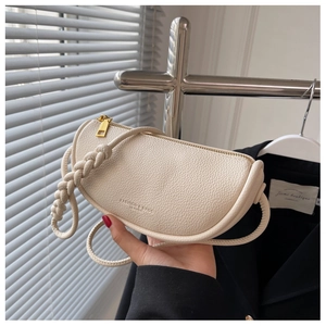 Detail of off-white lychee grain leather saddle bag with woven handle and gold zipper