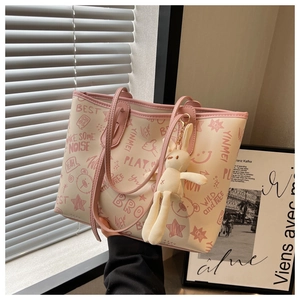Close-up of cream tote bag with pink graffiti patterns and a cute rabbit pendant