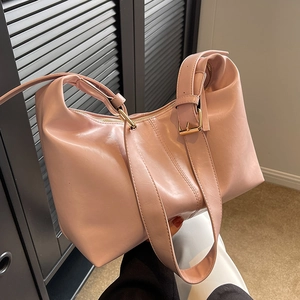 Pink leather hobo shoulder bag with textured surface and gold hardware in lifestyle setting